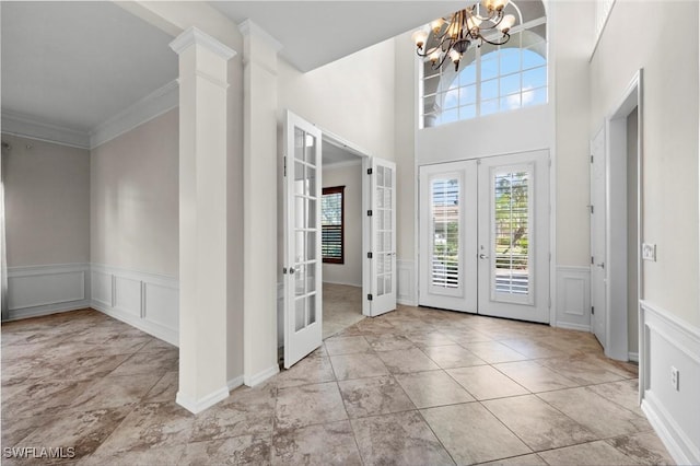 foyer entrance with ornamental molding, french doors, a chandelier, and light tile patterned flooring