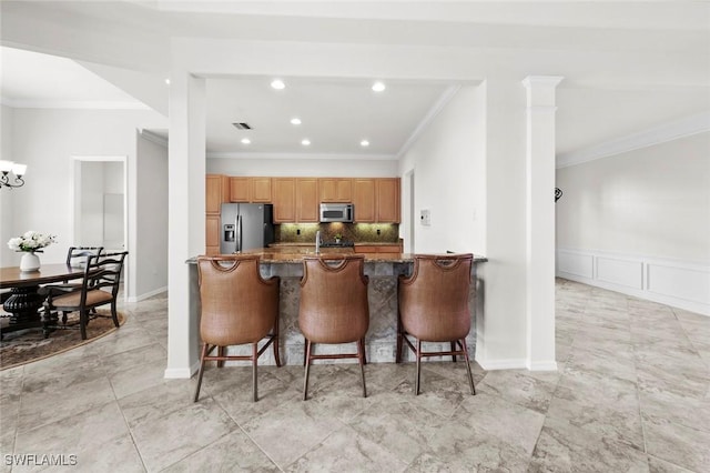 kitchen with tasteful backsplash, appliances with stainless steel finishes, a breakfast bar area, a peninsula, and crown molding