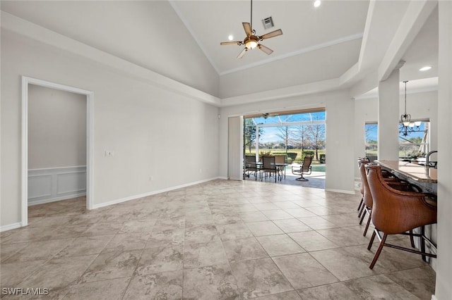 living area featuring visible vents, a decorative wall, light tile patterned flooring, high vaulted ceiling, and ceiling fan with notable chandelier