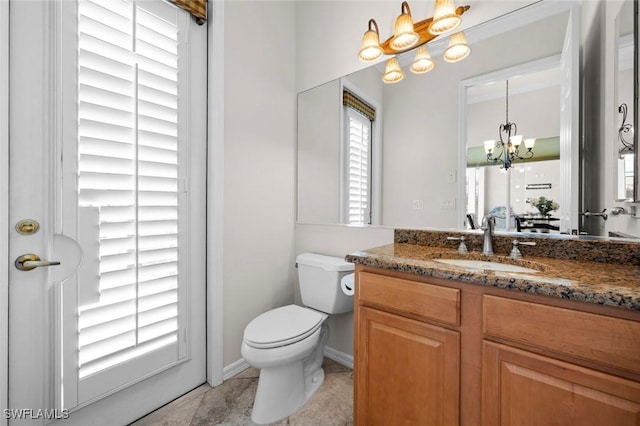 bathroom featuring a notable chandelier, vanity, and toilet