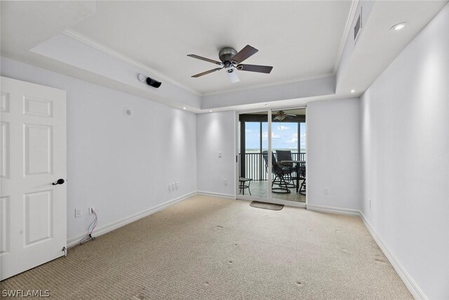 carpeted spare room with a tray ceiling, ceiling fan, and crown molding