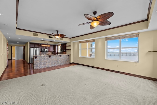 unfurnished living room featuring ceiling fan, crown molding, a tray ceiling, and wood-type flooring