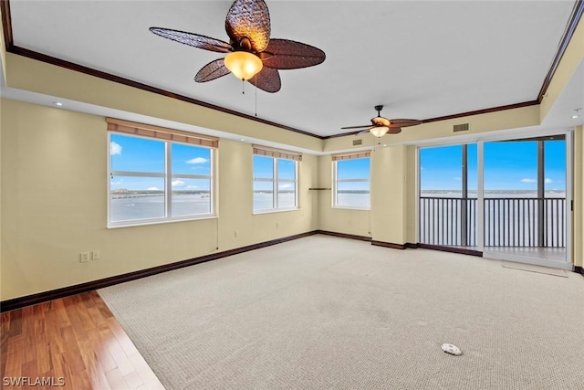 spare room with crown molding, baseboards, a ceiling fan, and plenty of natural light