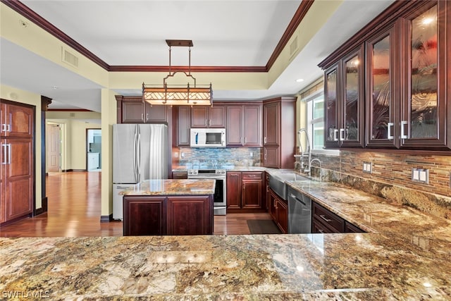 kitchen with dark hardwood / wood-style flooring, decorative backsplash, stainless steel appliances, light stone counters, and crown molding