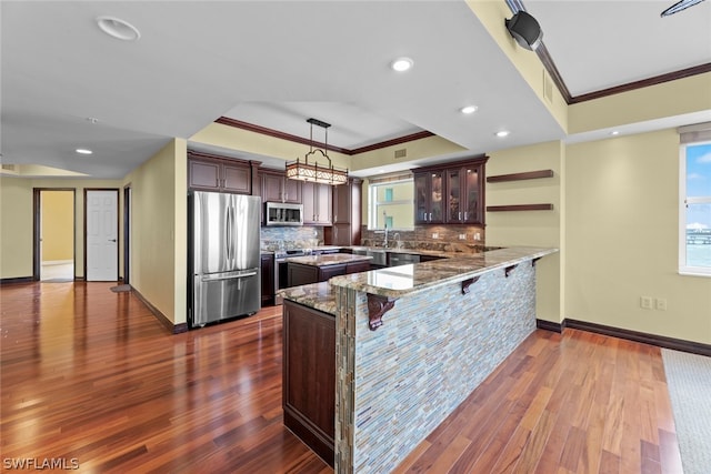 kitchen with kitchen peninsula, stainless steel appliances, dark hardwood / wood-style flooring, and tasteful backsplash