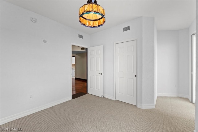 unfurnished bedroom with baseboards, carpet, and visible vents