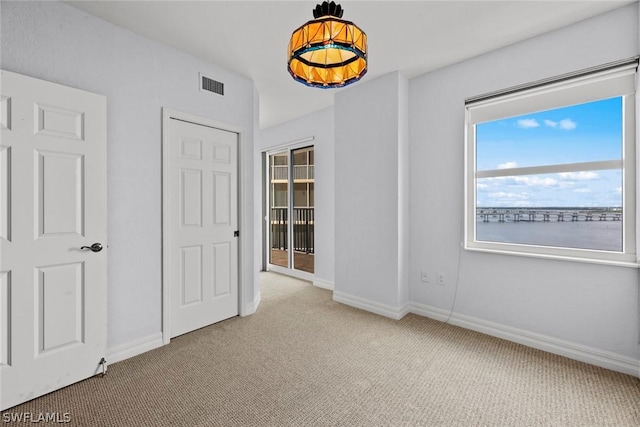 unfurnished bedroom with carpet flooring, baseboards, and visible vents