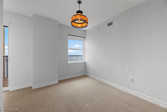 carpeted empty room featuring a textured wall, baseboards, and visible vents