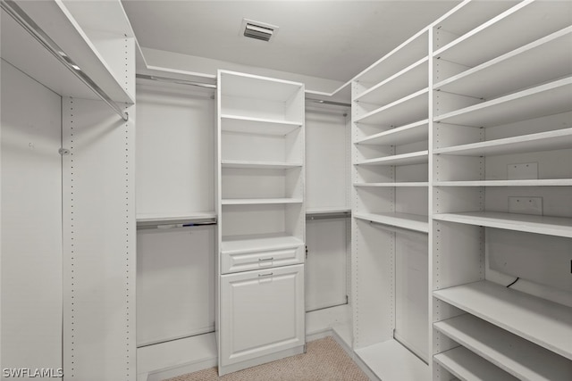 walk in closet featuring light colored carpet