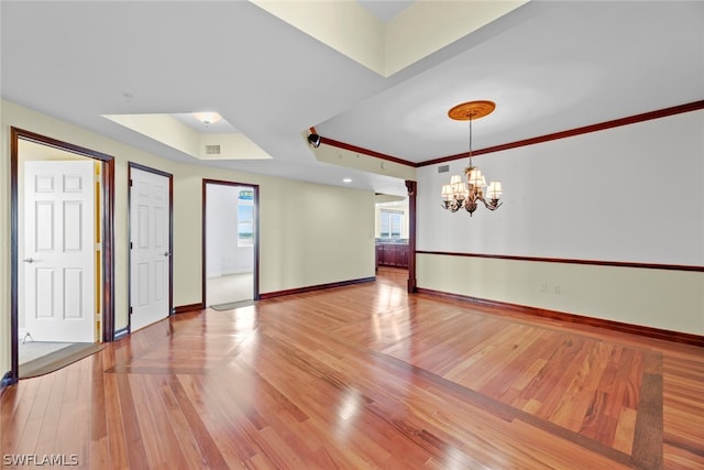 spare room featuring hardwood / wood-style floors, a chandelier, and ornamental molding