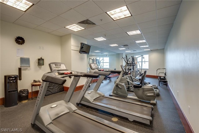 exercise room with visible vents, a drop ceiling, and baseboards