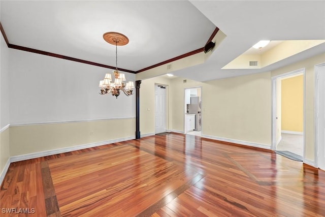 unfurnished dining area featuring baseboards, an inviting chandelier, crown molding, visible vents, and wood finished floors
