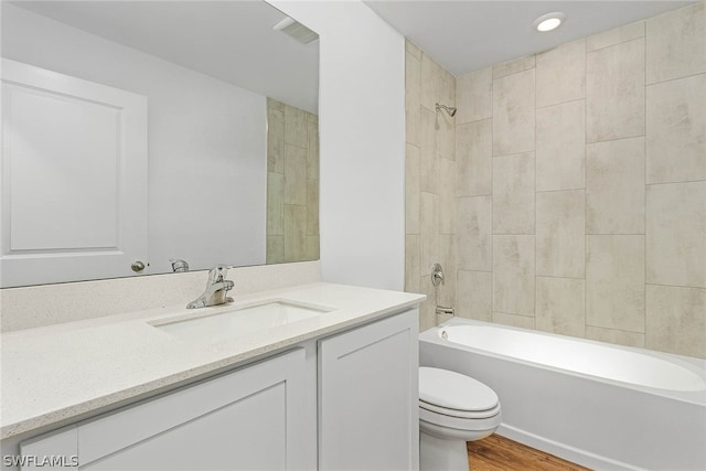 full bathroom with tiled shower / bath, vanity, toilet, and wood-type flooring