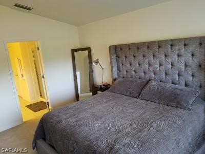 bedroom with ensuite bathroom and carpet floors