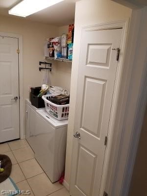 clothes washing area with independent washer and dryer and light tile flooring