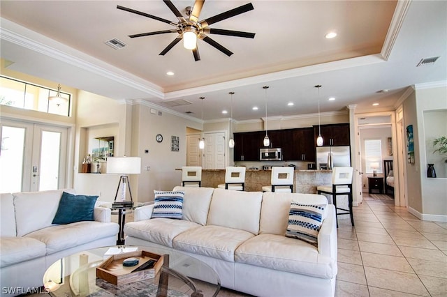 tiled living room with ceiling fan, french doors, crown molding, and a tray ceiling