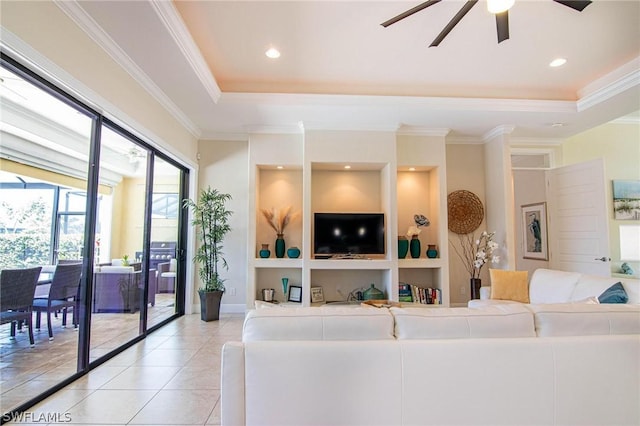 living room with a tray ceiling, ceiling fan, light tile patterned floors, and ornamental molding