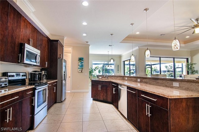 kitchen with ceiling fan, hanging light fixtures, stainless steel appliances, light stone counters, and a tray ceiling