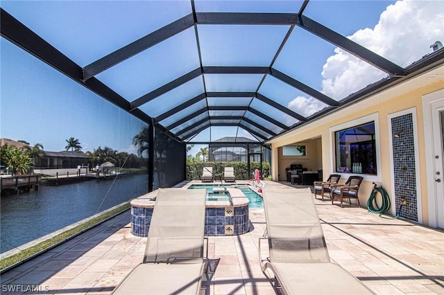 view of pool with an in ground hot tub, a patio, a water view, and glass enclosure