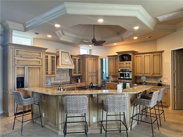 kitchen featuring premium range hood, backsplash, ceiling fan, light tile flooring, and a breakfast bar