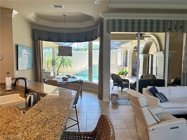 dining space with sink, ceiling fan, light tile floors, and a raised ceiling