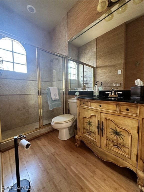 bathroom with walk in shower, toilet, vanity, and hardwood / wood-style floors