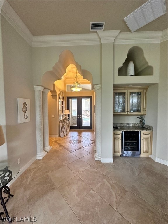 unfurnished living room with beverage cooler, french doors, decorative columns, and tile floors