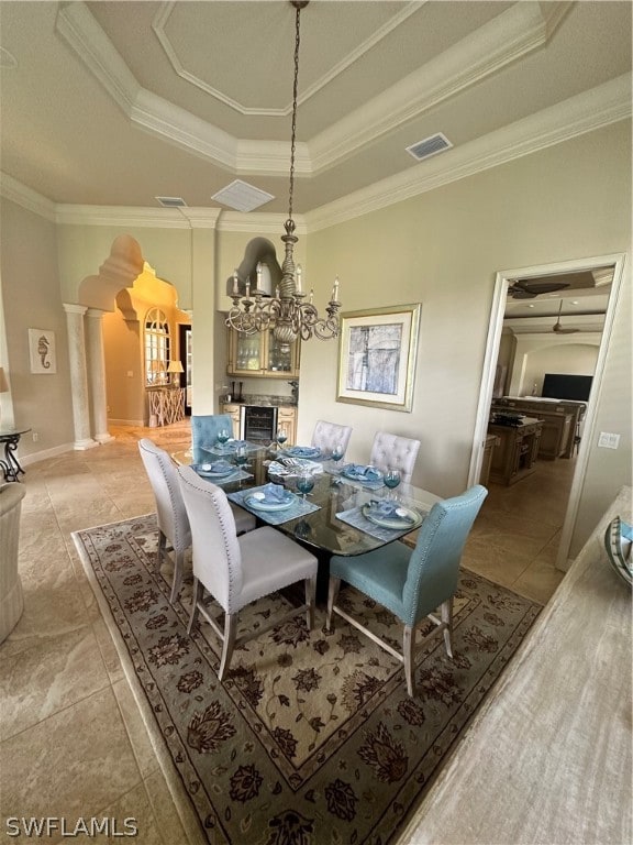 dining area featuring ornamental molding, ornate columns, tile floors, and a tray ceiling