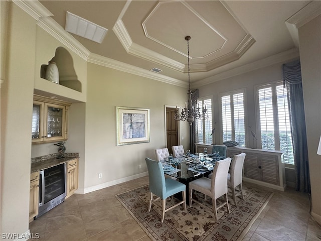 tiled dining space featuring ornamental molding, wine cooler, an inviting chandelier, and a raised ceiling