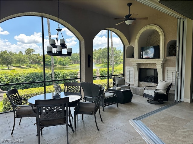 sunroom featuring ceiling fan with notable chandelier and exterior fireplace