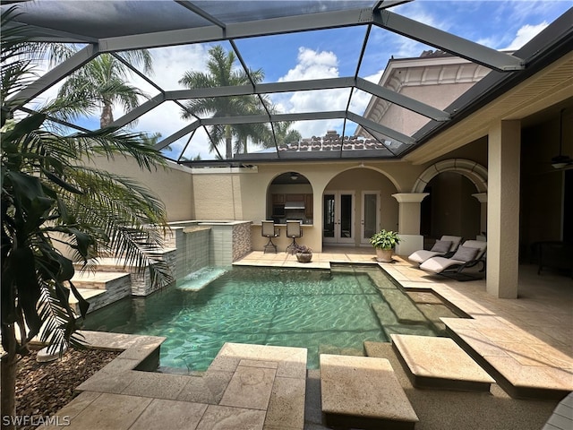 view of swimming pool featuring exterior kitchen, french doors, a lanai, a patio area, and pool water feature