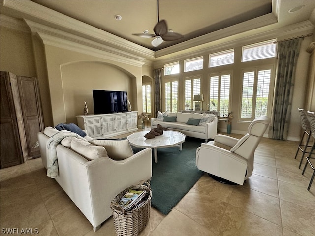 living room with crown molding, tile floors, ceiling fan, and a tray ceiling