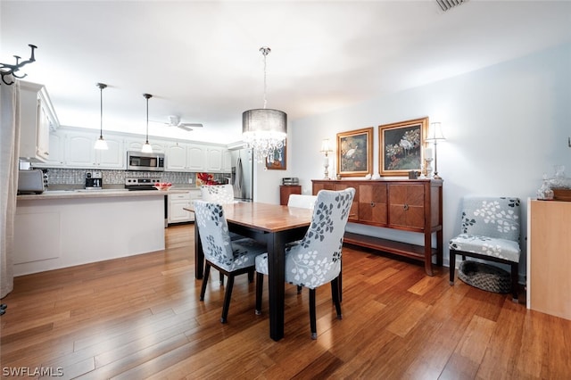 dining space with light hardwood / wood-style floors and a notable chandelier