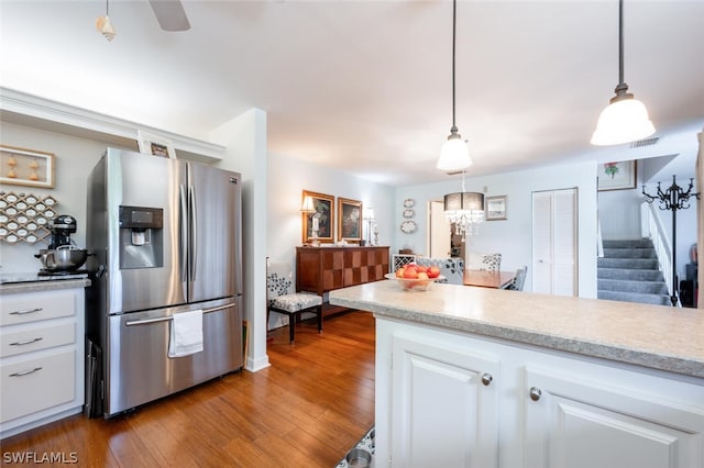 kitchen featuring white cabinets, hanging light fixtures, stainless steel fridge, and hardwood / wood-style flooring