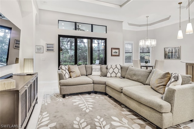 living room with an inviting chandelier, a towering ceiling, plenty of natural light, and a raised ceiling