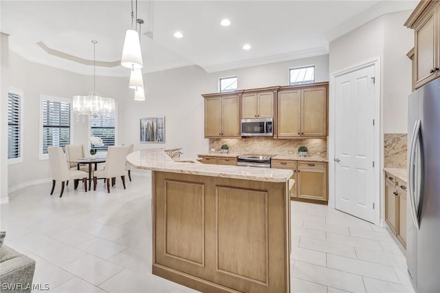 kitchen with appliances with stainless steel finishes, tasteful backsplash, light stone counters, a center island with sink, and decorative light fixtures