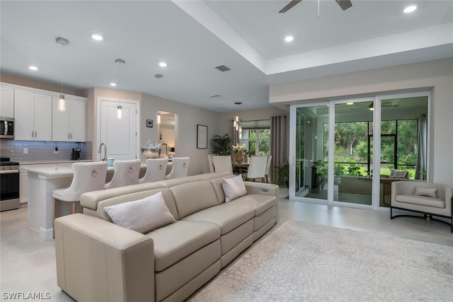 living room with sink, ceiling fan, and light tile flooring