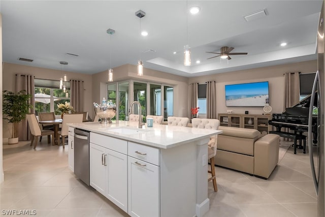 kitchen with stainless steel dishwasher, sink, decorative light fixtures, and a kitchen island with sink