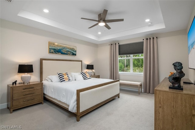 carpeted bedroom featuring ceiling fan and a tray ceiling