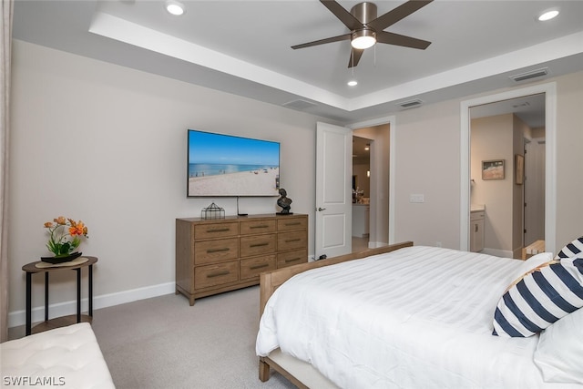 carpeted bedroom featuring ceiling fan, a tray ceiling, and connected bathroom