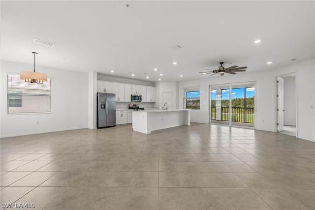 unfurnished living room featuring sink, ceiling fan, and light tile floors