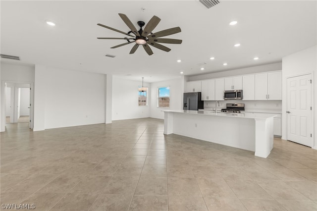 kitchen with ceiling fan, stainless steel appliances, a kitchen island with sink, and light tile floors