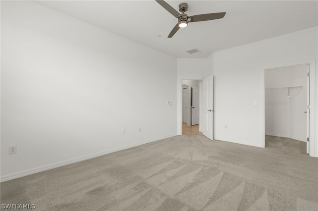 unfurnished bedroom with ceiling fan, a closet, light carpet, and a spacious closet