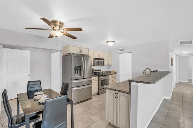 kitchen featuring cream cabinets, ceiling fan, stainless steel appliances, and light tile floors