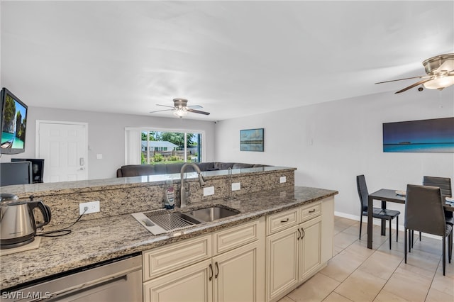 kitchen featuring light stone countertops, cream cabinets, sink, dishwasher, and ceiling fan