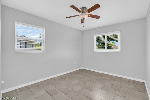 tiled spare room featuring a wealth of natural light and ceiling fan