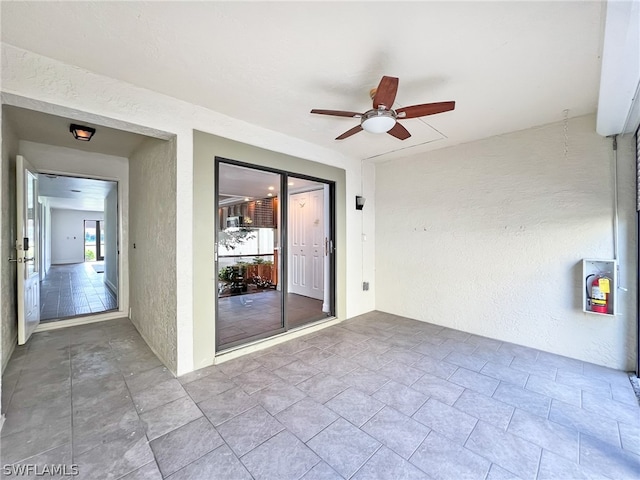 tiled empty room featuring ceiling fan