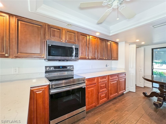 kitchen with appliances with stainless steel finishes, a raised ceiling, ceiling fan, and hardwood / wood-style flooring