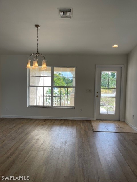 empty room featuring an inviting chandelier and hardwood / wood-style flooring