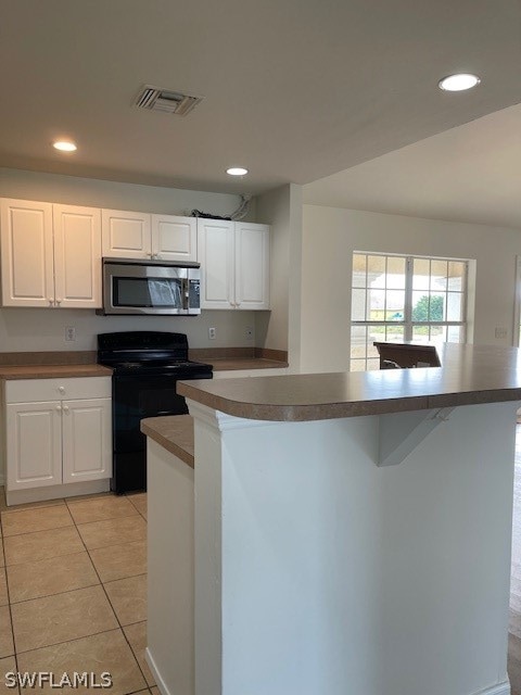 kitchen featuring white cabinets, black range with electric cooktop, light tile floors, and a kitchen island